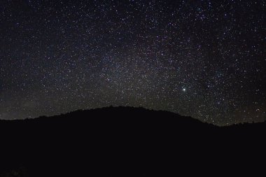 Night sky with stars and a mountain in the foreground. Astronomical abstract background