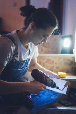 Young pretty woman doing wall repair at home using screwdriver