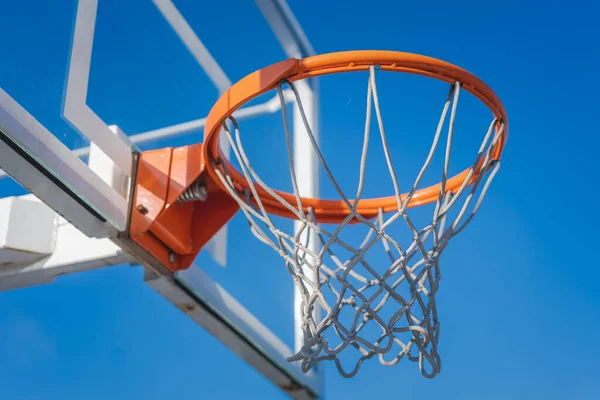 Basketball basket against the blue sky, sports ground in the city