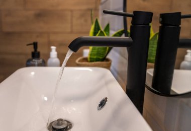 Water flowing from the faucet into the sink in the bathroom, water purity concept