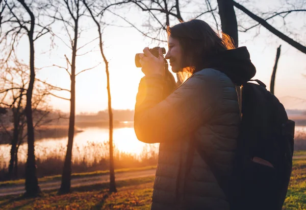 手にカメラを持った女性写真家と春の森に立つバックパック — ストック写真