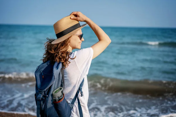 Deniz Kıyısında Duran Beyaz Tişörtlü Şapkalı Neşeli Genç Bir Kadın — Stok fotoğraf