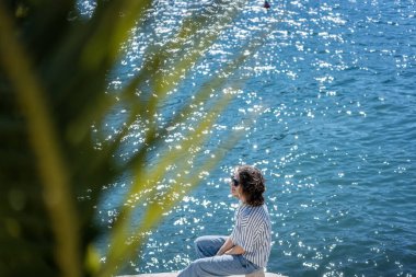 Güneş gözlüklü, plajda güneşlenen genç ve rahat bir kadın. Yaz tatilleri ve deniz seyahatleri