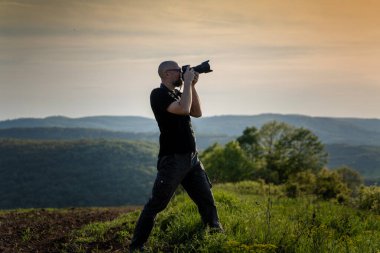 Yetişkin beyaz erkek gezgin profesyonel fotoğrafçı kamera önünde manzara fotoğrafı çekiyor.