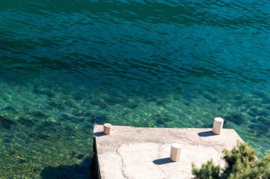 Gök mavisi denizin kıyısında, minimalist bir deniz manzarası.