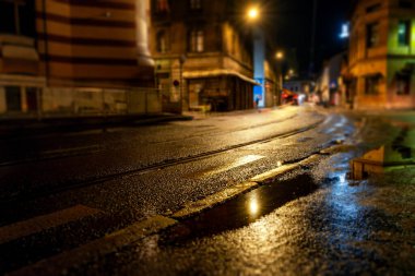 Gece yağmur yağdıktan sonra şehir caddesi. Fenerlerin ve yolun ışığı. Soyut şehir arkaplanı