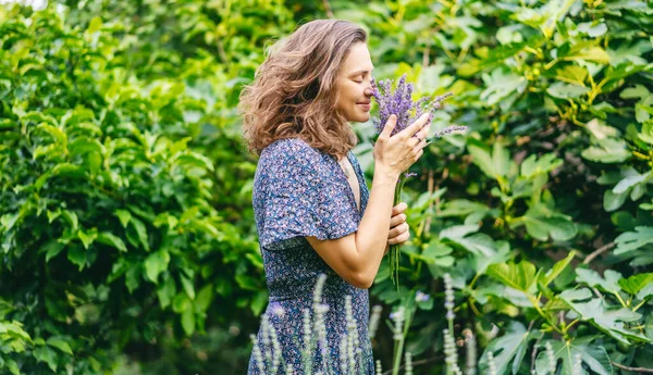 Młoda Szczęśliwa Kobieta Sukience Stojąca Ogrodzie Bukietem Lawendy Wdychająca Zapach — Zdjęcie stockowe