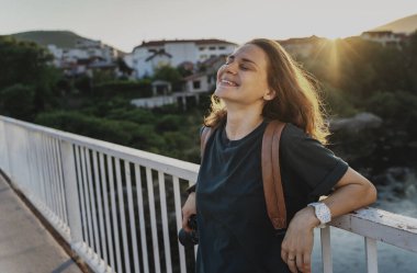 Genç ve mutlu bir kadının portresi Yaz şehrinde günbatımının tadını çıkarıyor