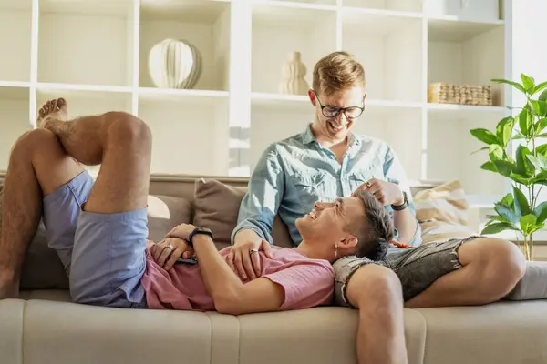 stock image Young happy cute gay couple spending time in a modern apartment talking on the sofa. LGBT family concept