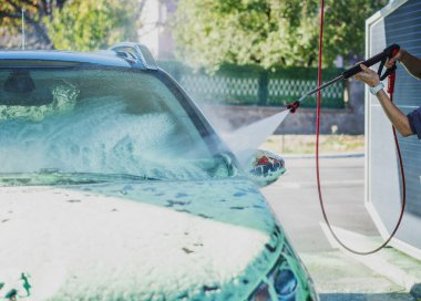 Kırsal kesimdeki self servis istasyonunda arabaya köpük süren bir kadın.