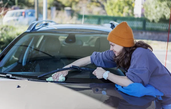 Woman wiping down car after washing car at self-service station