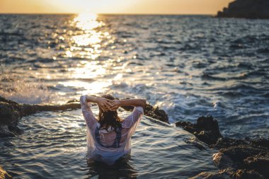 Deniz kıyısında doğal bir deniz banyosunda beyaz gömlekli, neşeli, rahat bir kadın. Thalasapi sağlıklılığı