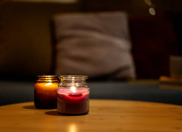 Scented candles in glass jars on a table in the living room near the sofa