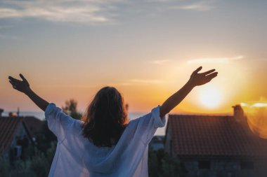 Genç ve neşeli bir kadın gün batımında güzel bir anın tadını çıkarıyor. Hayat konsepti.