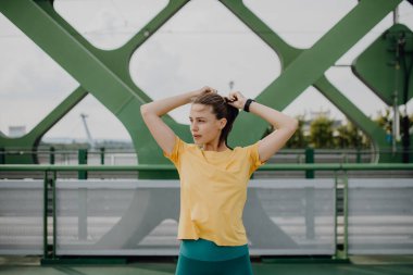 Portrait of young sportive woman resting outdoor in a city after running. clipart