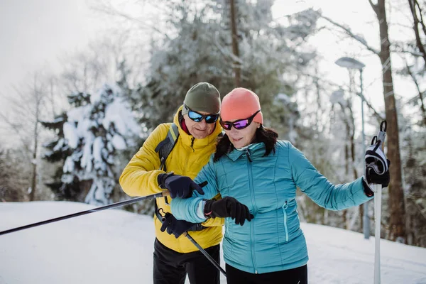 Senioren Paar Schaut Beim Winterskifahren Auf Eine Smartwatch — Stockfoto