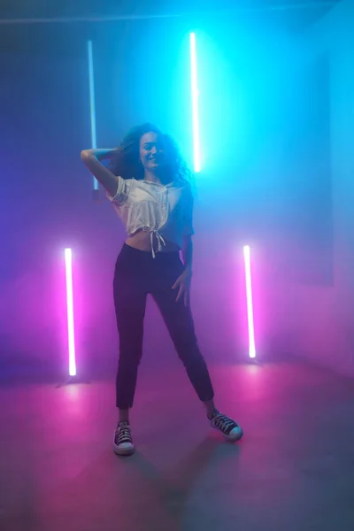 stock image A modern dance girl dancer dancing in neon light doing gymnastic exercises in studio, copy space.