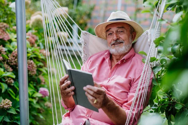 快乐的老人在花园里看书放松一下 — 图库照片