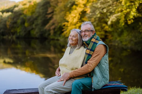秋の日に湖の近くのベンチに座って恋にシニアカップル — ストック写真