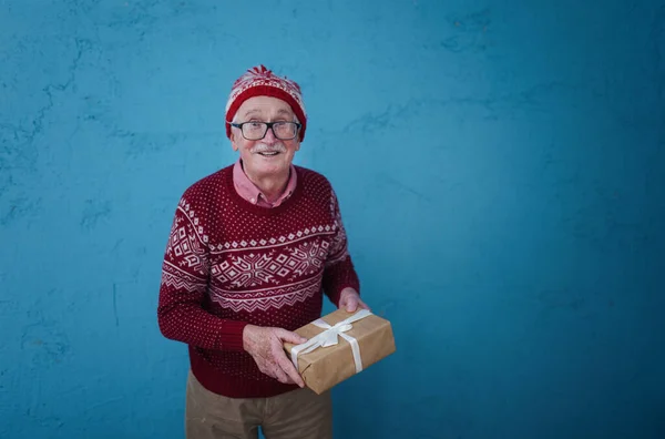 一个快乐的老人在蓝色背景面前带着礼物的画像 — 图库照片