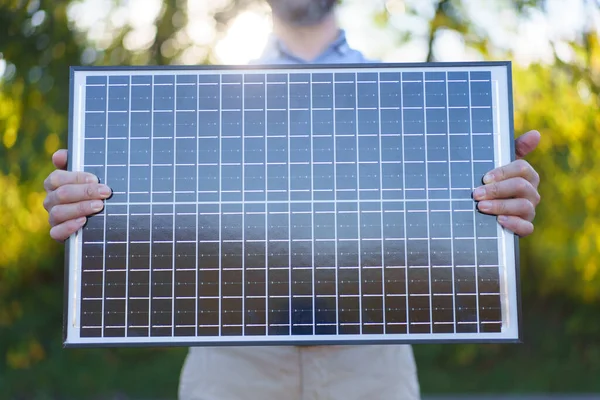 持太阳能电池板的商人站在花园外的特写镜头 — 图库照片