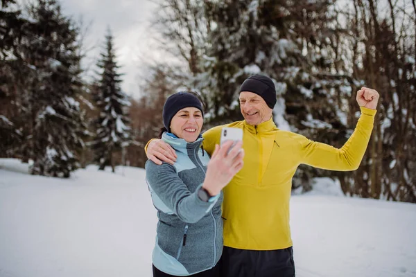 シニアカップル取り自撮り雪の自然でジョギング中 — ストック写真