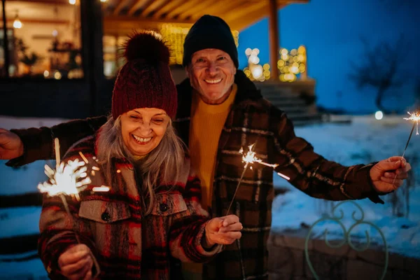 新年を祝う幸せな高齢者のカップルと輝き 冬の夜を楽しむ — ストック写真