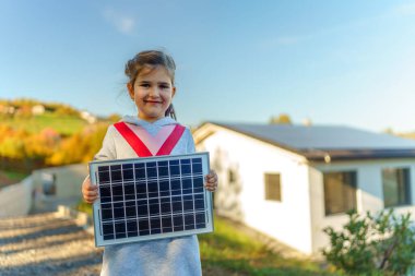 Küçük kız elinde fotovoltaik güneş paneli tutuyor. Alternatif enerji, tasarruf kaynakları ve sürdürülebilir yaşam tarzı kavramı.