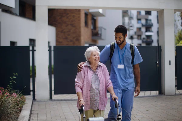 Bakıcı Huzurevinin Önünde Yaşlı Kadın Müşteriyle Yürüyor — Stok fotoğraf