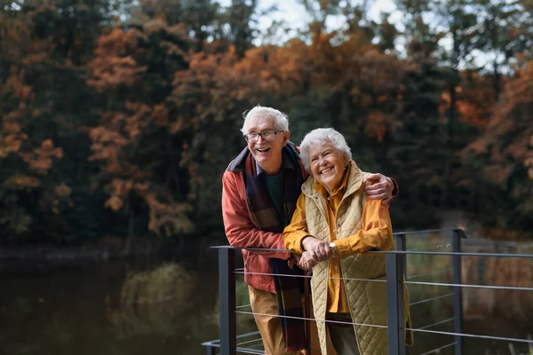 秋天里 一对快乐的老夫妇在湖边散步 休息片刻 — 图库照片