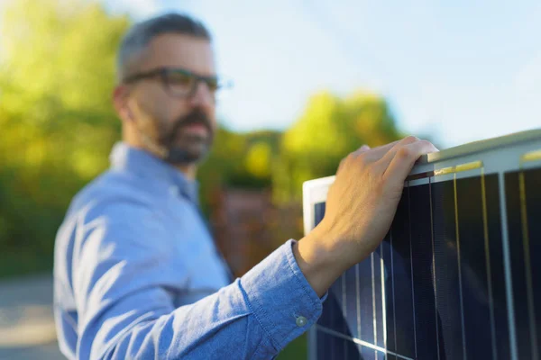 拿着太阳能电池板站在花园外的商人 — 图库照片