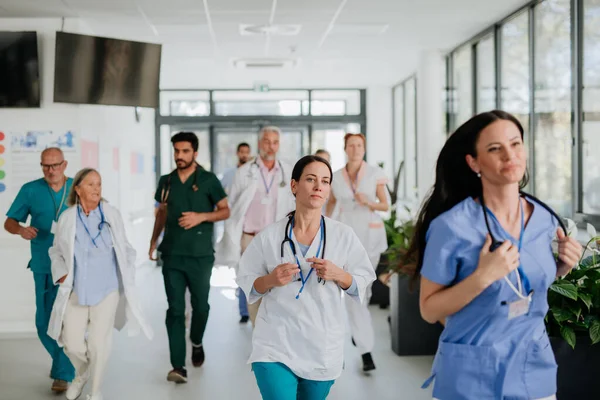 Young stressed doctors running at a hospital corridor.