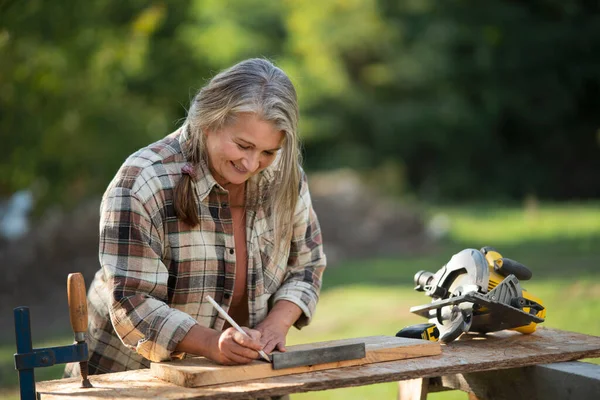 A handy female carpenter working in carpentry diy workshop outdoors.