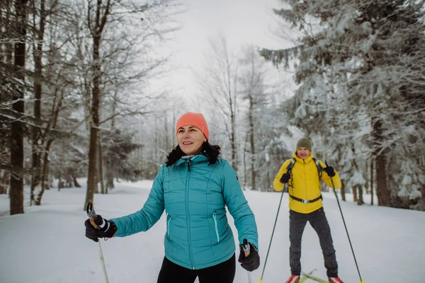 雪の森の中で一緒にシニアカップルスキー — ストック写真