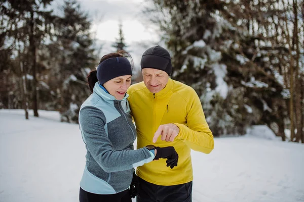 Seniorenpaar Schaut Sich Beim Winterlauf Eine Smartwatch — Stockfoto