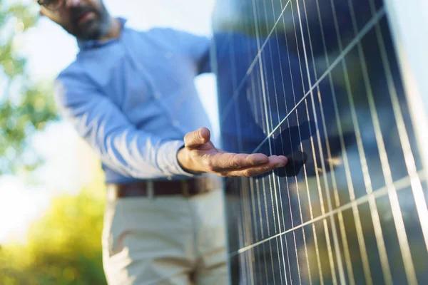 商人手持并解释太阳能电池板是如何工作的 站在花园的室外 — 图库照片