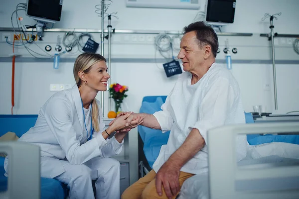 年轻的女医生牵着手 在病房里和她的病人交谈 — 图库照片