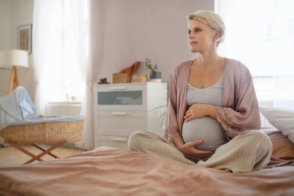 Mutlu Hamile Kadın Yatakta Oturarak Karnını Okşuyor — Stok fotoğraf