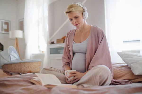 Ciężarna Kobieta Siedzi Łóżku Słucha Muzyki Czyta Książkę Bawiąc Się — Zdjęcie stockowe