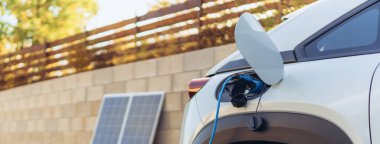 Bir elektrikli otomobili ev fotovoltaik elektrik santralinden şarj etmek, sürdürülebilir ve ekonomik ulaşım kavramı.