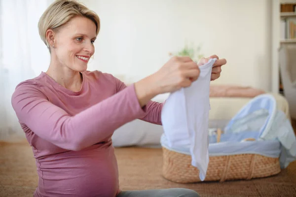 Lycklig Gravid Kvinna Tittar Små Baby Kläder — Stockfoto
