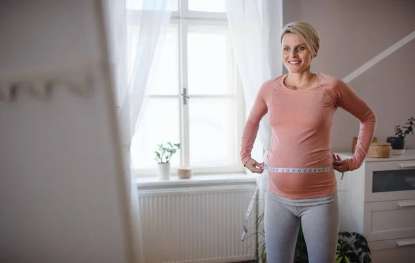 Glückliche Frau Misst Ihren Schwangeren Bauch Vor Dem Spiegel — Stockfoto