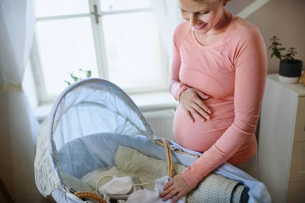 Ευτυχισμένη Έγκυος Γυναίκα Που Κοιτάζει Μικρά Μωρουδιακά Ρούχα — Φωτογραφία Αρχείου
