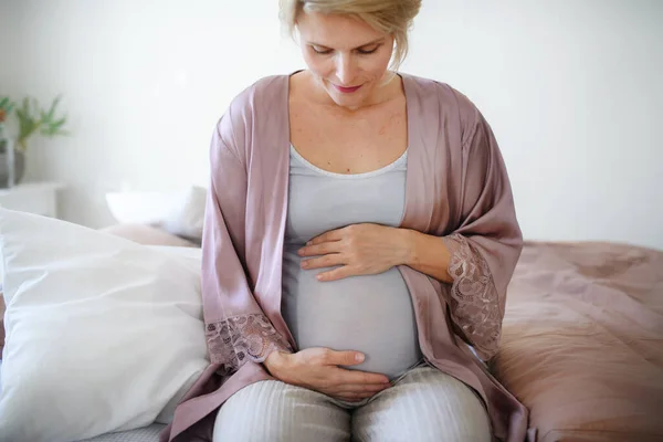 Šťastná Těhotná Žena Hladí Své Břicho Sedí Posteli — Stock fotografie