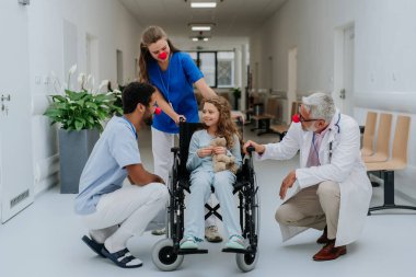 Küçük kızla ilgilenen kırmızı burunlu mutlu doktorlar..