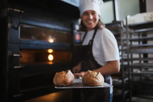 stock image Happy young baker with fresh bread, in a bakery.