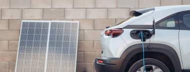 Bir elektrikli otomobili ev fotovoltaik elektrik santralinden şarj etmek, sürdürülebilir ve ekonomik ulaşım kavramı.