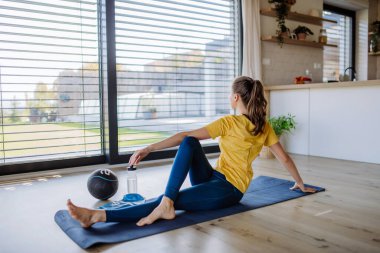 Young woman doing exercises at home. clipart