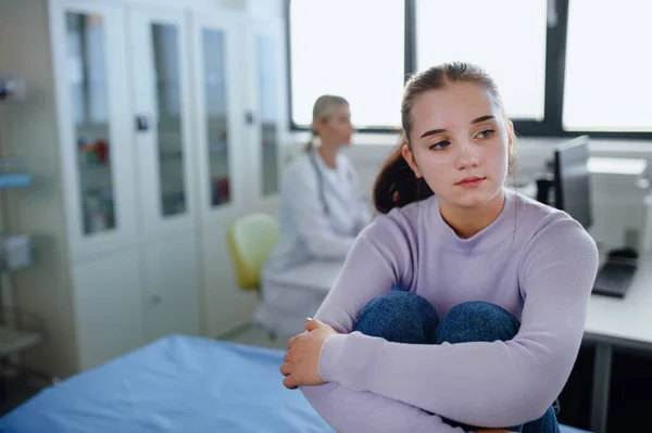 stock image Unhappy teenage girl sitting in a doctors office.