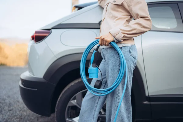 Kadının Elinde Arabasından Elektrik Kablosu Tutarken Onu Evde Şarj Etmeye — Stok fotoğraf